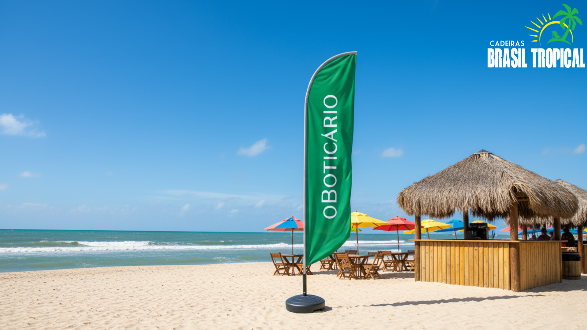 Praia ensolarada com bandeira verde do O Boticário ao lado de quiosque de palha, mesas e guarda-sóis coloridos à beira-mar.