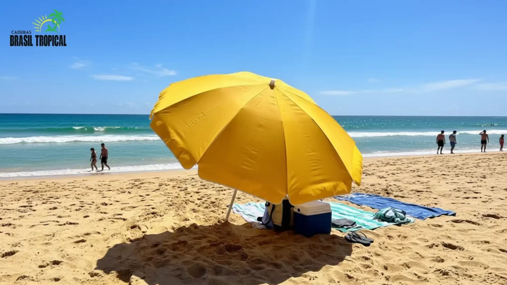 Guarda sol amarelo da Cadeiras Brasil Tropical aberto na praia, criando sombra ampla em um dia ensolarado à beira-mar.
